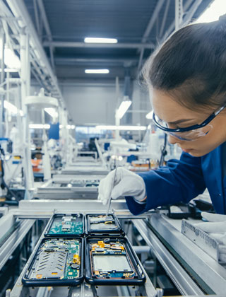 A worker is assembling printed circuit boards while standing on the electronics assembly line. High-tech EMS facility.