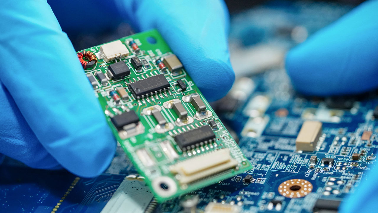 Technician handling commercial PCB with precision for cost-effective electronics manufacturing and quality assurance