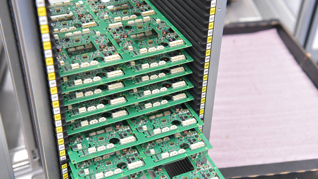 Rack of assembled industrial PCBs organized for quality control and scalable electronics manufacturing