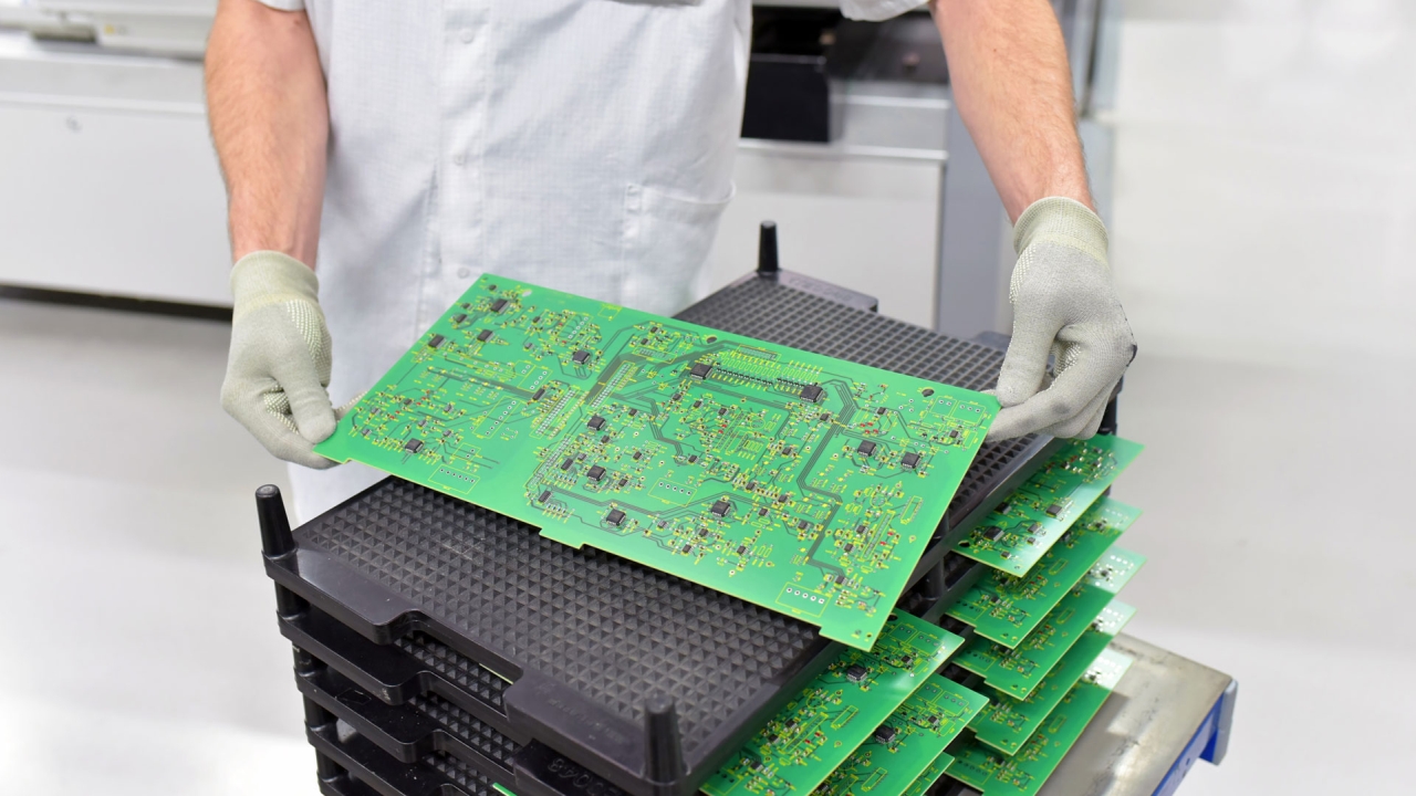 Technician handling PCB in clean manufacturing environment for reliable agricultural electronics and quality assurance