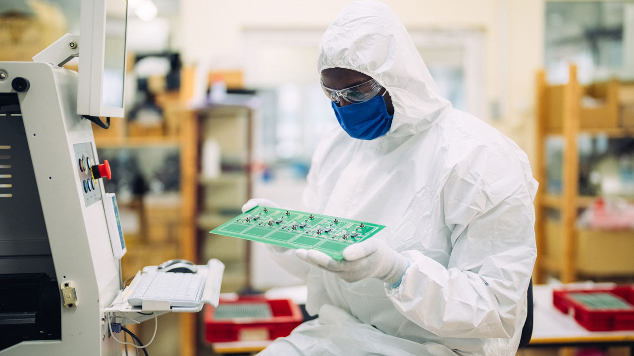 Technician inspecting PCB for rugged agricultural electronics with precision and contamination-free handling