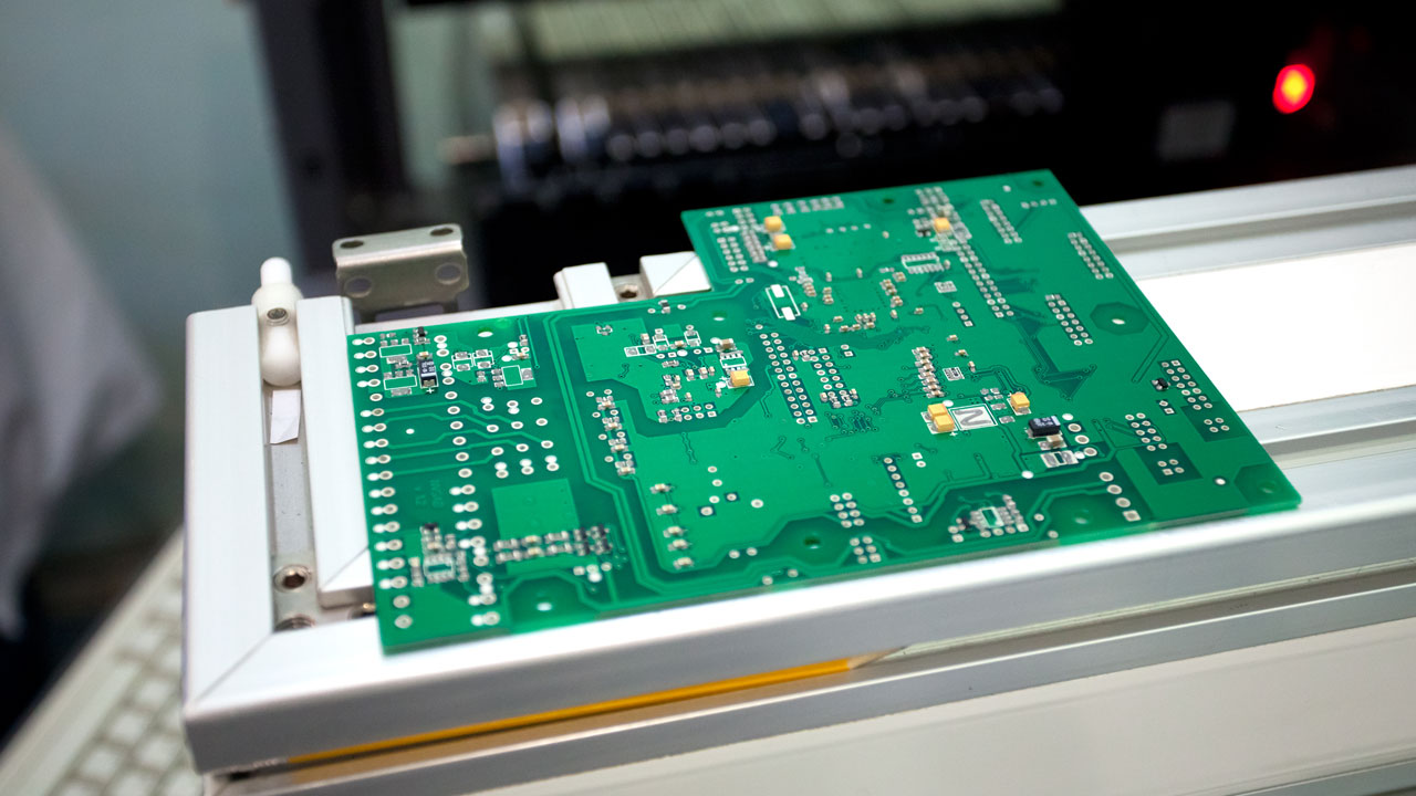 Unpopulated industrial PCB on assembly fixture during early-stage electronics manufacturing for automation systems