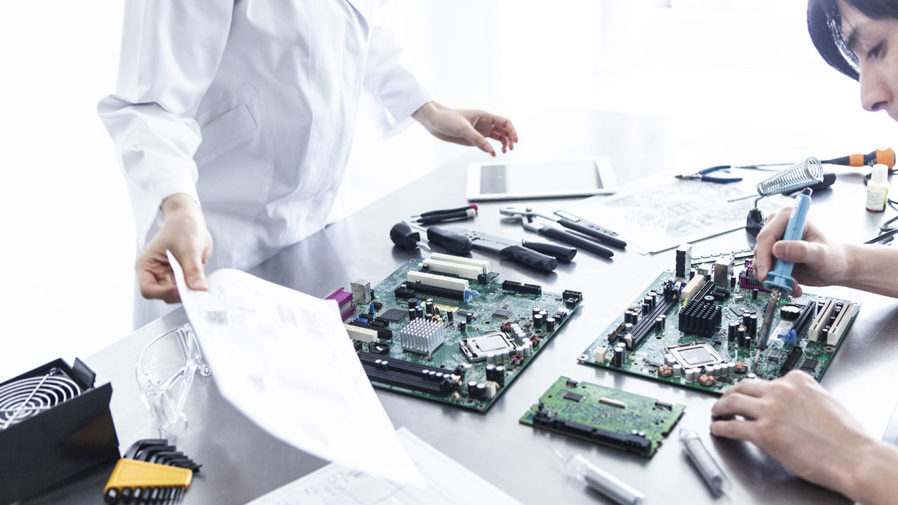 Technicians assembling and validating telecom and networking PCB systems with schematics and precision tools in electronics lab